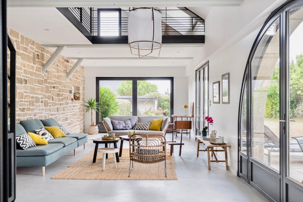 House in Brittany | Living room with mezzanine, stone wall and exposed beams | Interior Designers